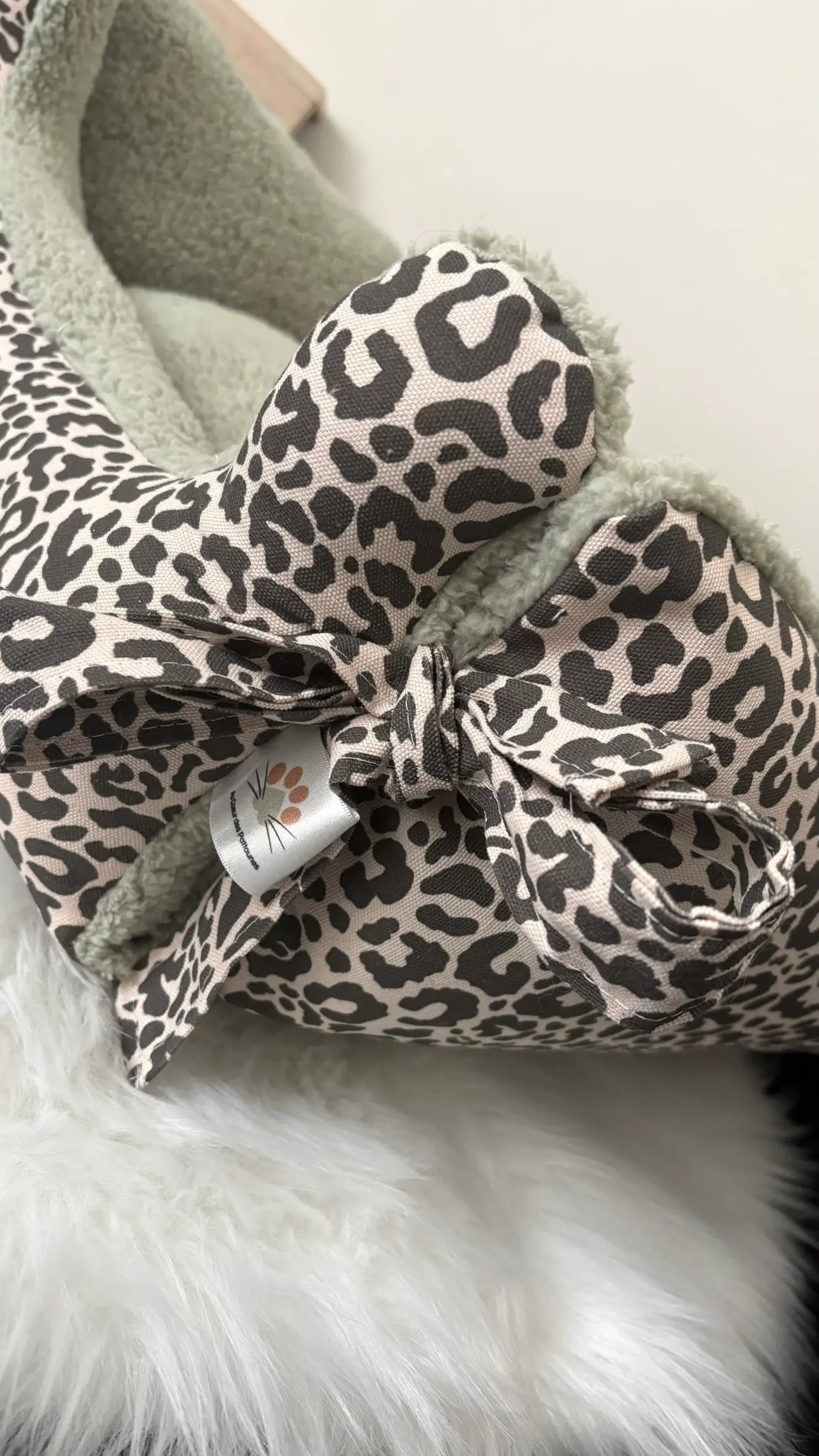 Dodo pour chiens et chat en bachette léopard noire et blanche et en sherpa verte avec nouage sur les côtés zoom sur ce détail