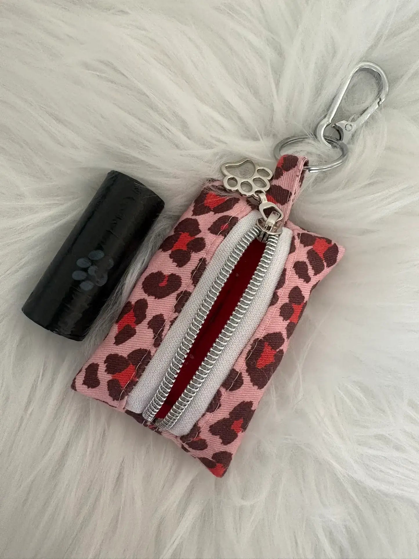 Distributeur de sacs à crottes fait main aux motifs léopard rouge et finitions argentées avec mousqueton et curseur patte de chat, vue doublure intérieure rouge. Capacité : un rouleau de sacs à déjections canines, un rouleau de sacs offert.