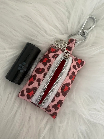 Distributeur de sacs à crottes fait main aux motifs léopard rouge et finitions argentées avec mousqueton et curseur patte de chat, vue doublure intérieure rouge. Capacité : un rouleau de sacs à déjections canines, un rouleau de sacs offert.