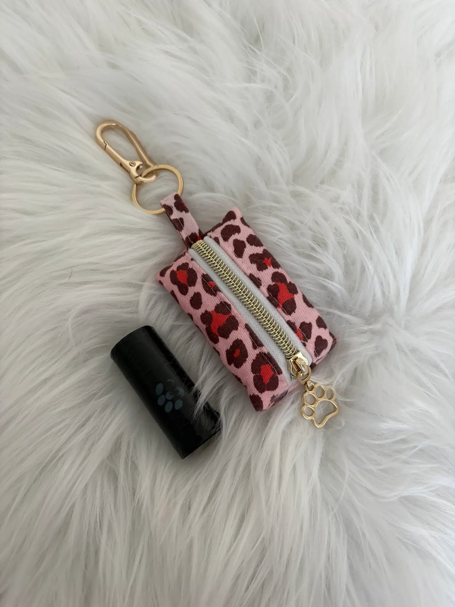 Distributeur de sacs à crottes fait main aux motifs léopard rouge et finitions dorées avec mousqueton et curseur patte de chat. Capacité : un rouleau de sacs à déjections canines, un rouleau de sacs offert