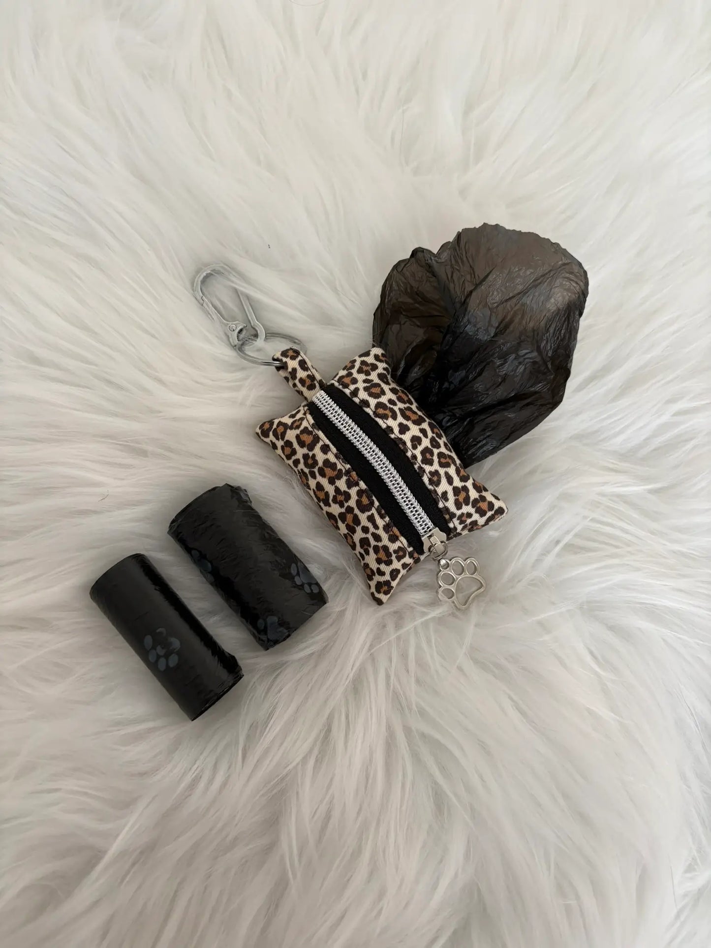 Distributeur de sacs à crottes fait main aux motifs léopard beige et finitions argentées avec mousqueton et curseur patte de chat, fermeture noire, vue sacs installés. Capacité : deux rouleaux de sacs à déjections canines, deux rouleaux de sacs offerts