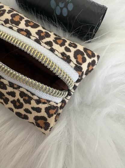 Distributeur de sacs à crottes fait main aux motifs léopard beige et finitions dorées avec mousqueton et curseur patte de chat, fermeture blanche, vue doublure marron. Capacité : un rouleau de sacs à déjections canines, un rouleau de sacs offert