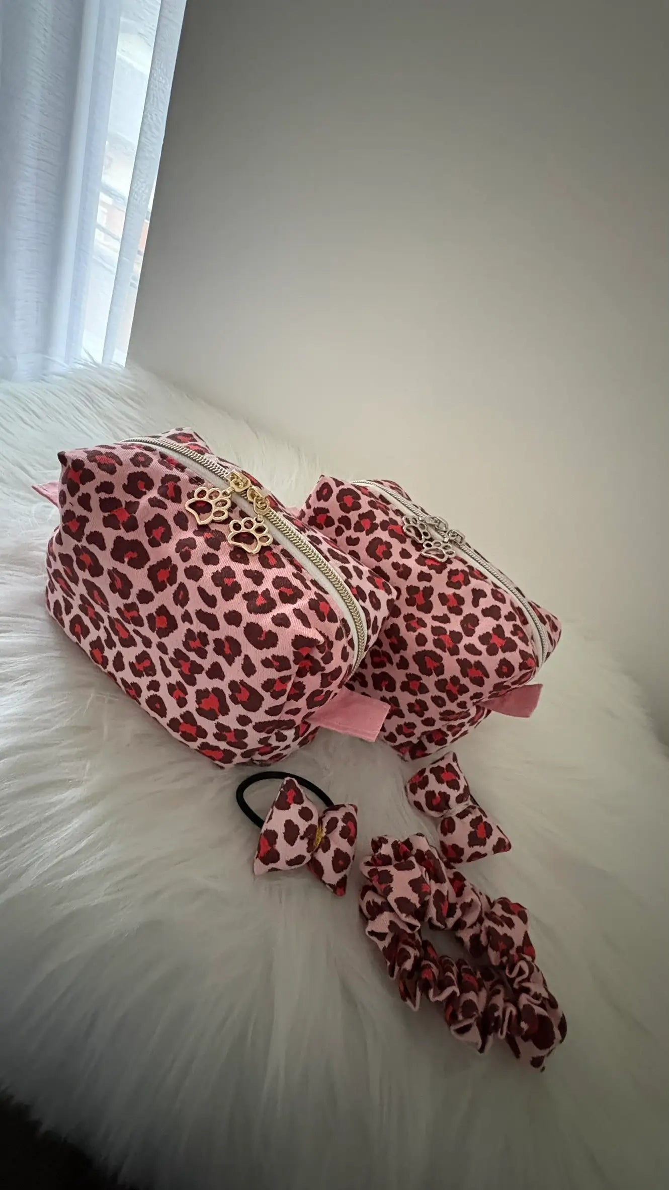 Duo de trousses à maquillages léopards rouges et roses, avec fermetures éclairs dorées ou agentés, et chouchous assortis pour visualisation de la collection.