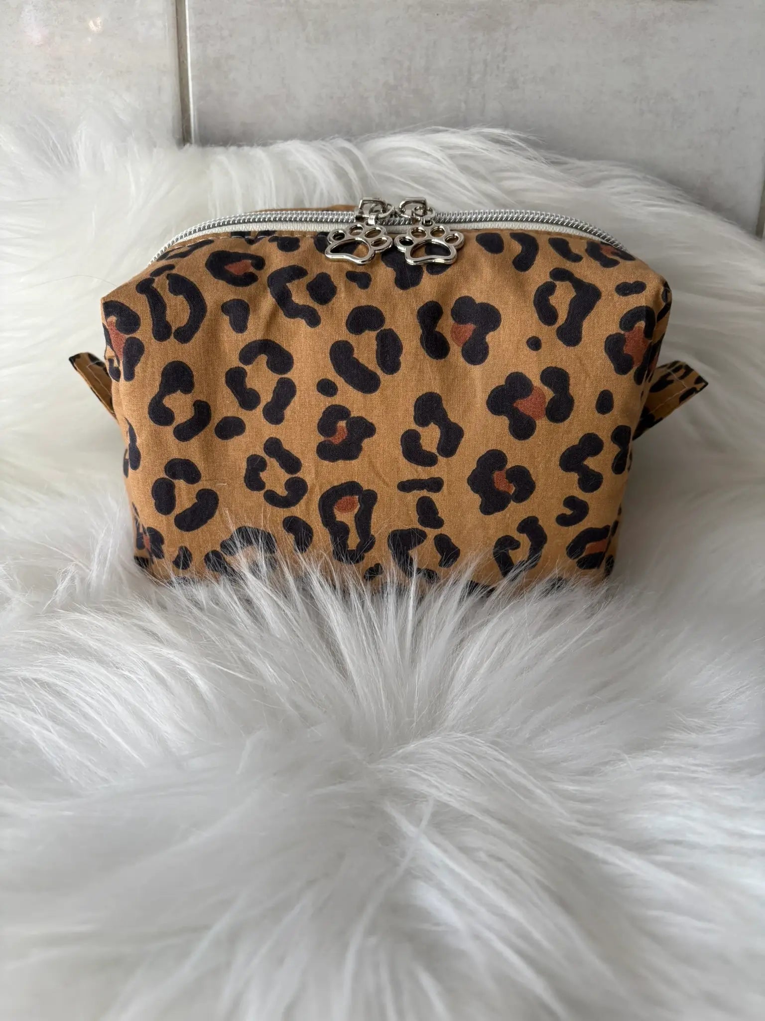 Trousse à maquillage artisanale à motifs léopard marron, avec fermeture éclair et deux curseurs pattes de chat argentés vue de face