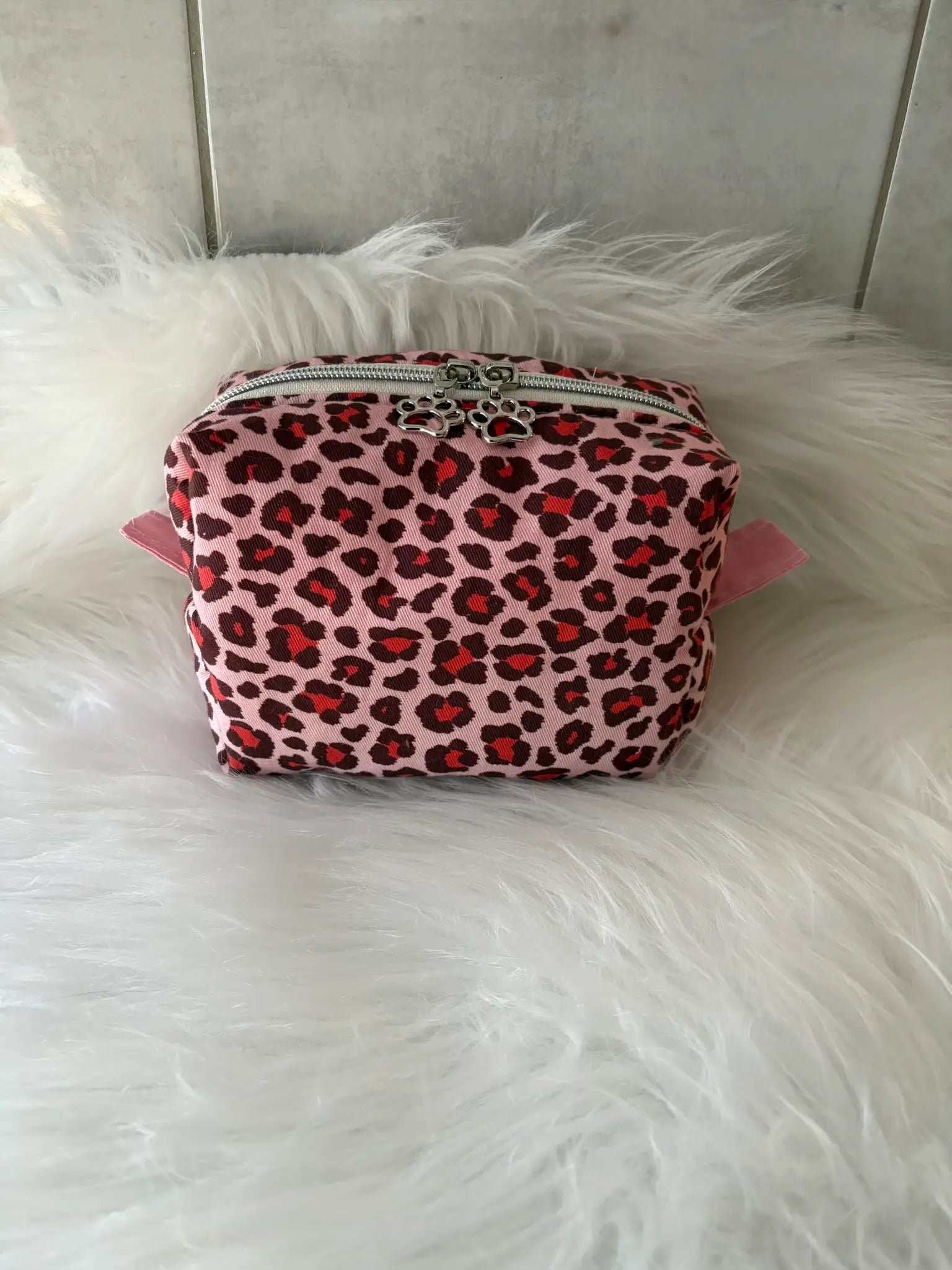 Trousse à maquillage artisanale aux motifs léopards roses et rouges, avec fermeture éclaire et deux curseurs pattes de chat argentés
