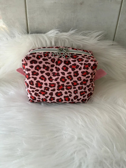 Trousse à maquillage artisanale aux motifs léopards roses et rouges, avec fermeture éclaire et deux curseurs pattes de chat argentés