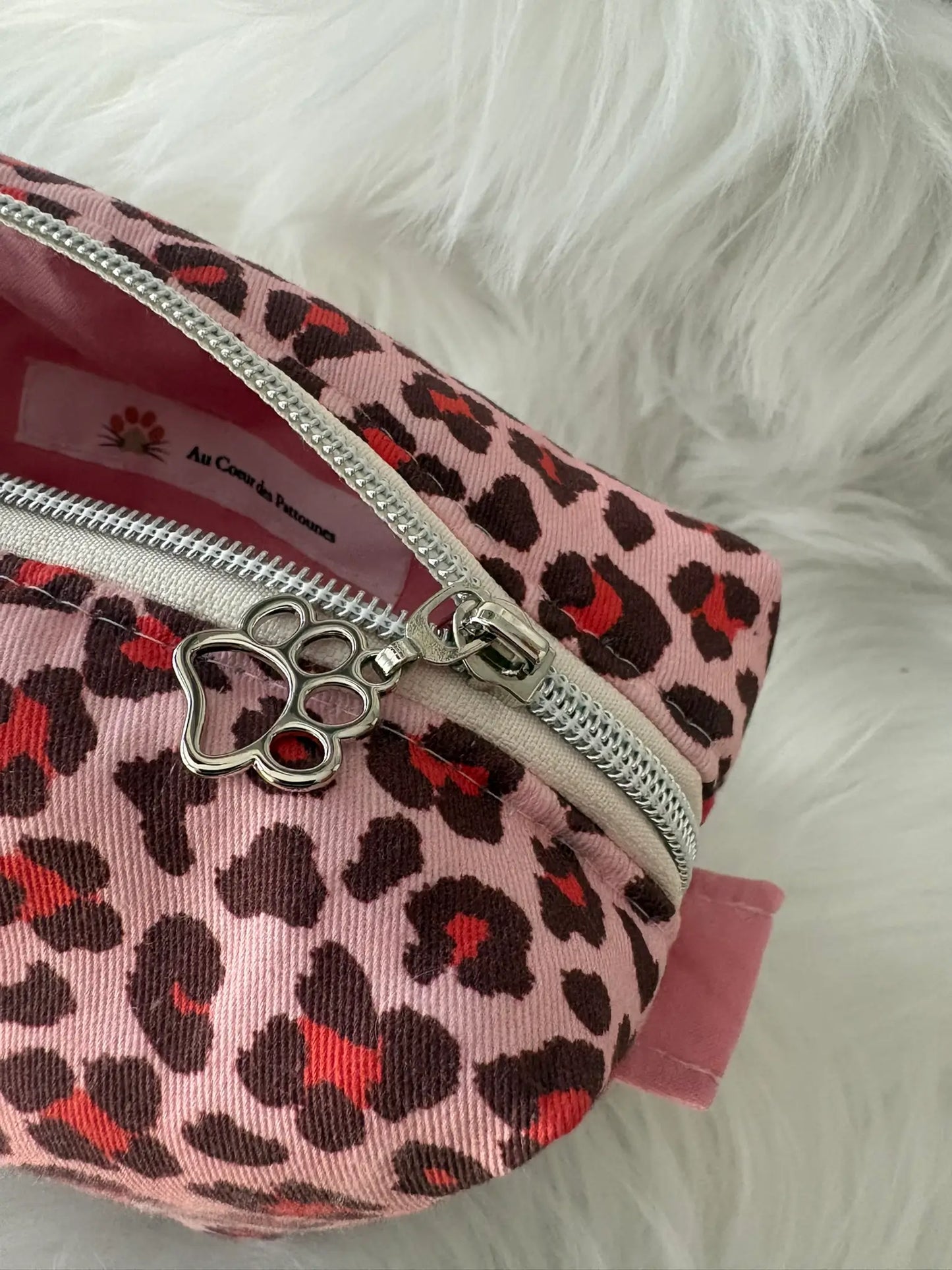 Trousse à maquillage artisanale aux motifs léopards roses et rouges, avec fermeture éclaire et deux curseurs pattes de chat argentés,vue intérieure