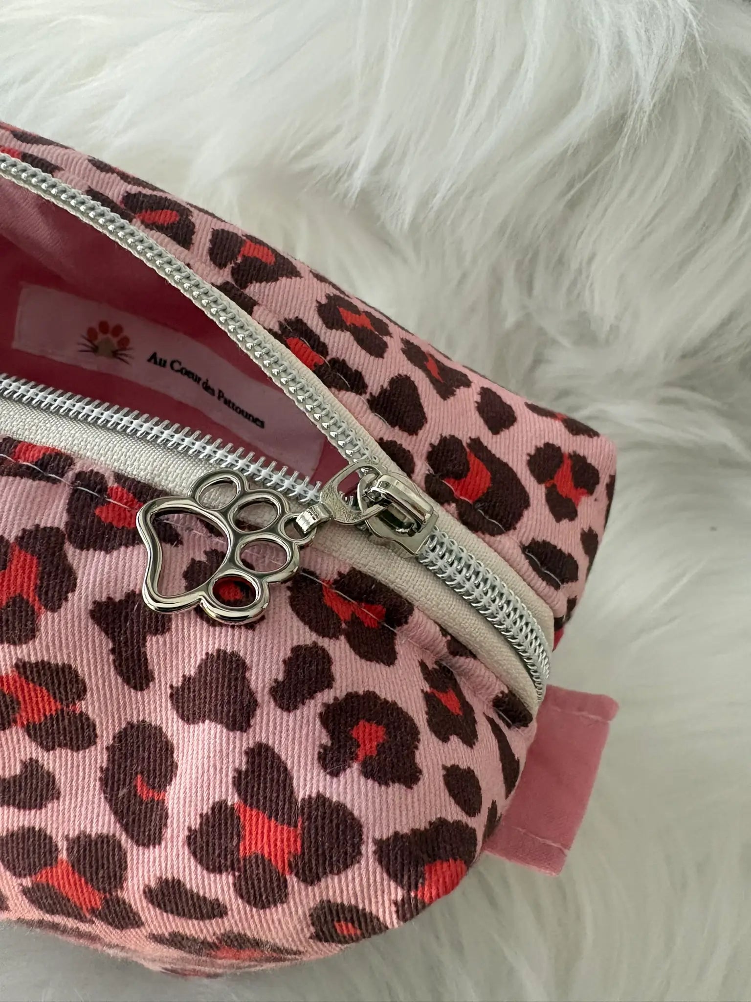 Trousse à maquillage artisanale aux motifs léopards roses et rouges, avec fermeture éclaire et deux curseurs pattes de chat argentés,vue intérieure
