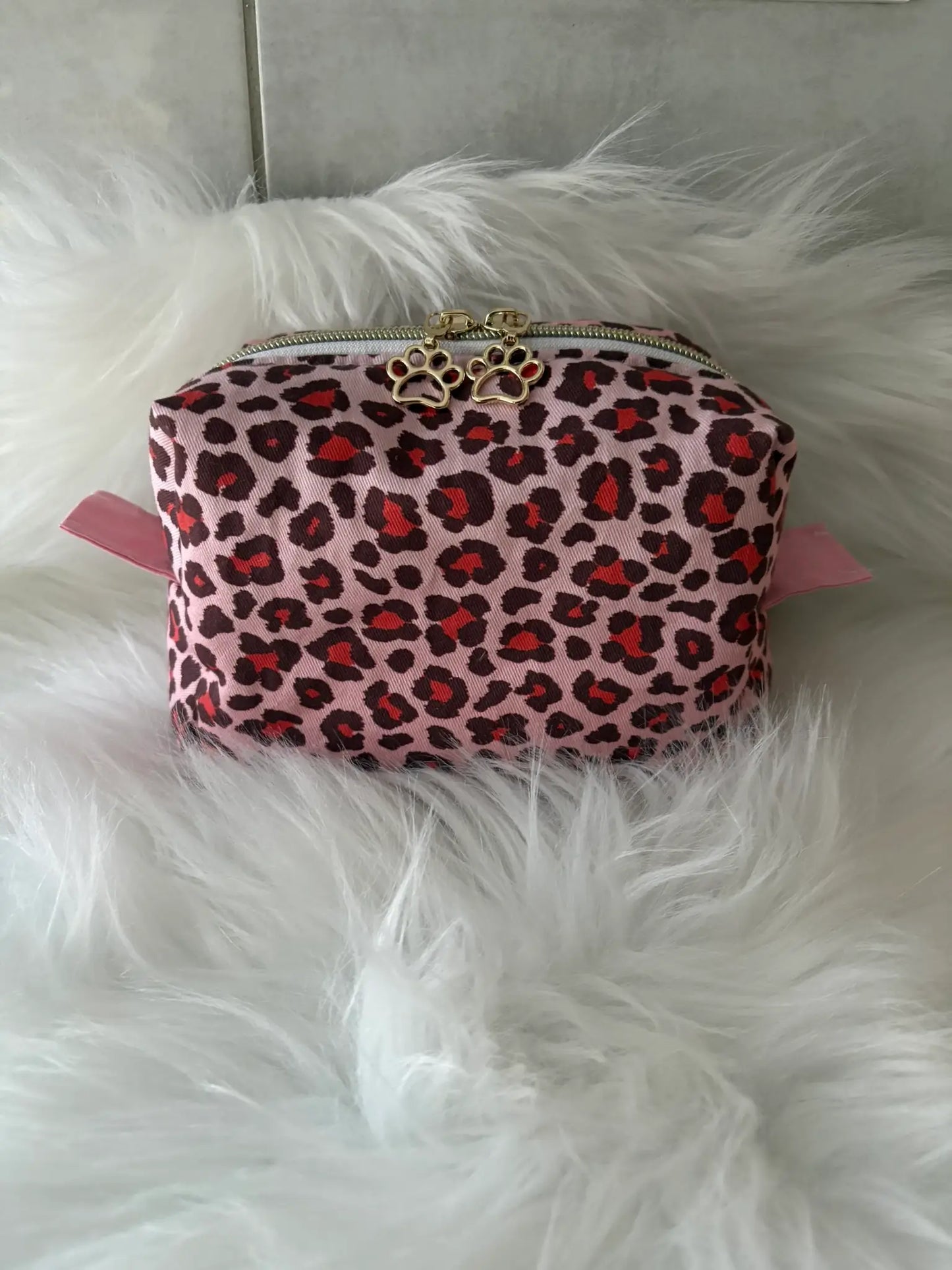 Trousse à maquillage artisanale aux motifs léopards roses et rouges, avec fermeture éclaire et deux curseurs pattes de chat dorés