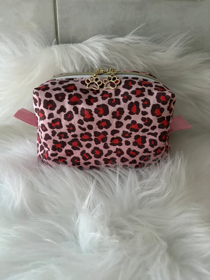 Trousse à maquillage artisanale aux motifs léopards roses et rouges, avec fermeture éclaire et deux curseurs pattes de chat dorés